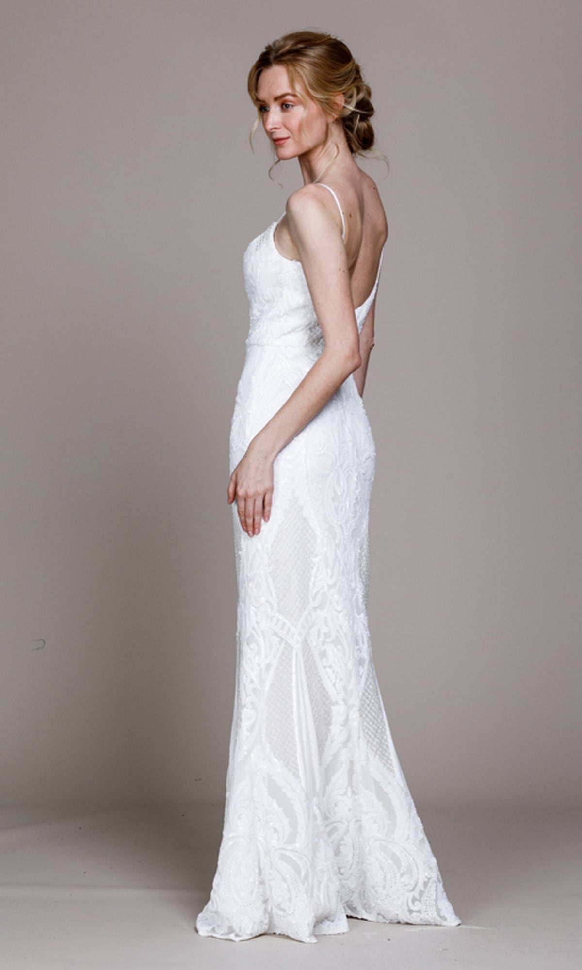 A woman stands in profile wearing the Sequin-Print Sleek Long Prom Dress 791, a fitted, floor-length gown with thin straps and a deep v-back, against a plain background.
